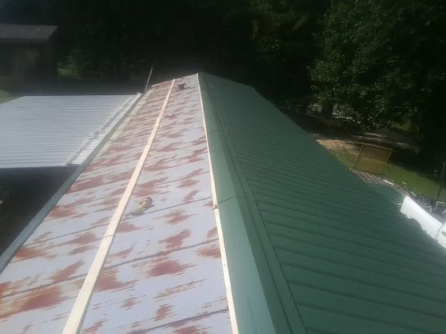 Old rusted panels beside newly installed green metal roofing — Wind Damage Roof Repair by Roofing Brothers in Woodward