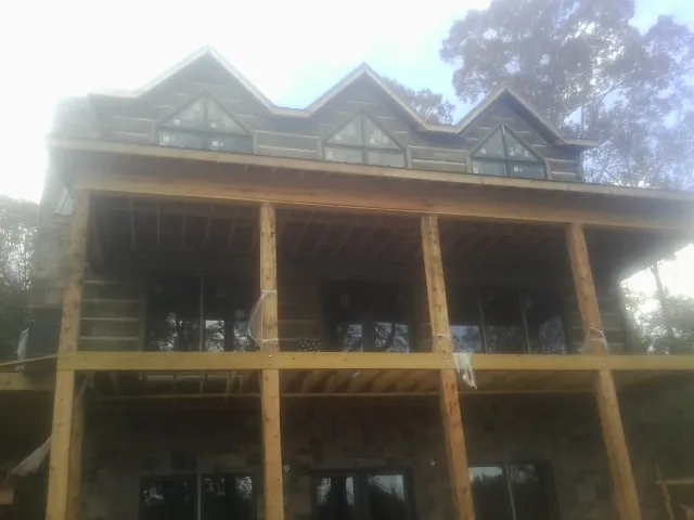 Dormers and porch framing on a large log home under construction — Roof Coating work by our crew in Woodward