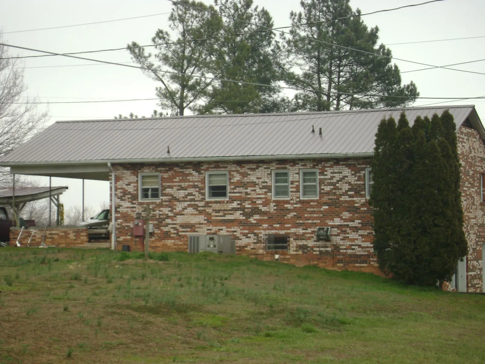 Gray metal roof on a brick split level home with a carport in Woodward